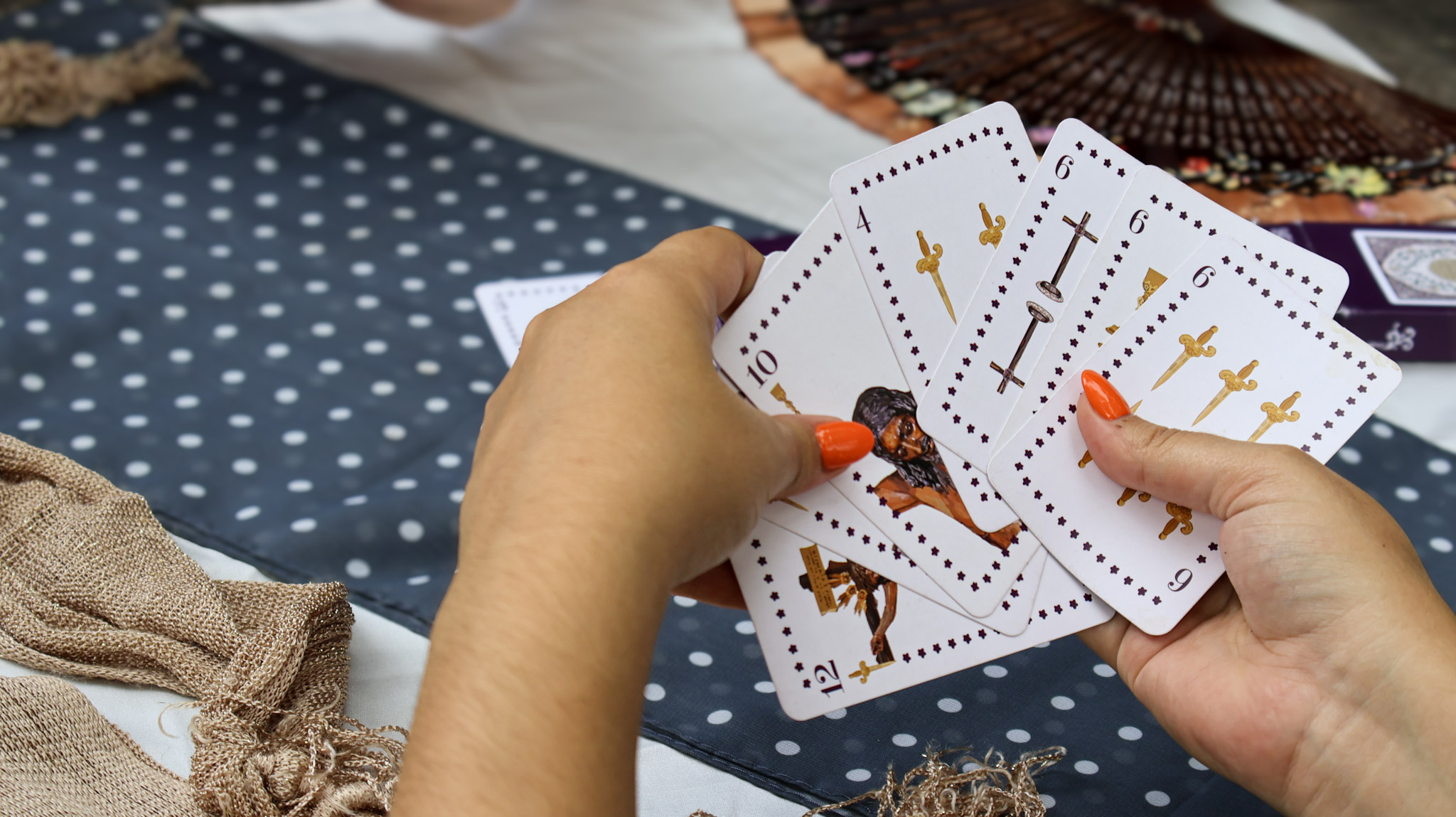 Manos sosteniendo baraja de cartas ilustrada Semana Santa de Málaga